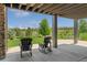 Covered patio boasts serene views of the manicured lawn, community, and ample seating at 10826 Evergold Way, Highlands Ranch, CO 80126