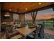 A covered deck has an outdoor dining area and a seating area with sunset views and stone pillars at 10826 Evergold Way, Highlands Ranch, CO 80126