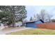 Side view of a blue home with a fenced yard, large tree, and an attached garage at 901 Delphi Dr, Lafayette, CO 80026