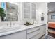 Modern bathroom featuring double sinks, white cabinets, a large mirror and a peek into the main bedroom at 3039 N Milwaukee St, Denver, CO 80205