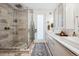 Bright bathroom featuring a glass shower, double sinks, white cabinets and decorative rug accenting the tile floor at 3039 N Milwaukee St, Denver, CO 80205