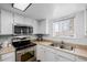 A kitchen featuring stainless steel appliances, white cabinets, a double sink, and a bright windowed sink area at 4922 S Rifle Ct, Aurora, CO 80015