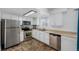 A kitchen featuring stainless steel appliances, white cabinets, tile floors, and a bright, windowed sink area at 4922 S Rifle Ct, Aurora, CO 80015