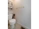 Half bathroom features a standard toilet, golden towel rack, and overhead storage shelves at 4648 S Abilene Cir, Aurora, CO 80015