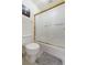 Bright bathroom featuring a bathtub with glass doors, a toilet, and soft gray rug at 4648 S Abilene Cir, Aurora, CO 80015