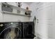 Laundry room showcasing modern black washer and dryer units with bright white shelves at 4648 S Abilene Cir, Aurora, CO 80015