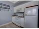 Compact kitchen with white cabinets and appliances, with a view into the laundry area at 12914 Ironstone Way # 201, Parker, CO 80134