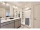 Modern bathroom with double sinks, quartz countertops, framed mirrors, a glass-enclosed shower, and updated fixtures at 27425 E Byers Pl, Aurora, CO 80018