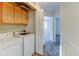 Convenient laundry room features washer, dryer, upper cabinets and doorway to hallway and carpeted bedroom beyond at 7450 Lowell Blvd # B, Westminster, CO 80030