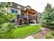 Spacious backyard featuring a covered patio, lush lawn, mature trees, and tiered landscaping at 2115 Holmby Ct, Castle Rock, CO 80104