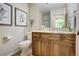 Bathroom featuring a wood vanity, granite countertop, toilet, decorative prints, and modern fixtures at 74 Blue Heron Dr, Greenwood Village, CO 80121