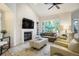 Bright living room featuring a fireplace, ceiling fan, and large windows showcasing outdoor views at 74 Blue Heron Dr, Greenwood Village, CO 80121