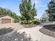 Long driveway leading to a spacious garage and home entrance, landscaped with trees and shrubs at 6449 E 163Rd Ave, Brighton, CO 80602