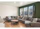 Spacious living room featuring a large sectional sofa, wood floors, and bright windows at 45810 Laceleaf Dr, Bennett, CO 80102