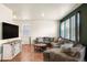 Comfortable living room features wood floors, a large sectional sofa, and plenty of natural light at 45810 Laceleaf Dr, Bennett, CO 80102