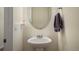 Well-lit powder room featuring a pedestal sink with an oval mirror and decorative towel holder at 45810 Laceleaf Dr, Bennett, CO 80102