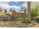 A backyard featuring a play structure, mature trees, and a classic brick home at 1900 Magnolia St, Denver, CO 80220