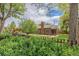 A classic brick home sits beyond a picket fence, showcasing its inviting backyard and mature trees at 1900 Magnolia St, Denver, CO 80220