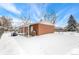 A snowy backyard with a covered patio and a grill at 6371 Iris Ct, Arvada, CO 80004