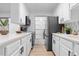 Galley kitchen with white cabinets, black hardware, stainless steel refrigerator, and a window overlooking the laundry at 12054 E 3Rd Ave, Aurora, CO 80011