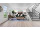 Bright living room features a teal sofa, wood floors, and modern staircase at 12054 E 3Rd Ave, Aurora, CO 80011