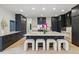 Modern kitchen featuring a large marble island with seating, stylish pendant lights, and sleek black cabinetry at 2921 Newton St, Denver, CO 80211