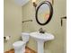 Classic bathroom with pedestal sink and a round mirror, and mosaic tile floor at 5722 W Chestnut Ave, Littleton, CO 80128