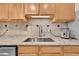 Kitchen counter featuring tile backsplash, stainless steel sink and faucet with an undermount ice maker at 5722 W Chestnut Ave, Littleton, CO 80128