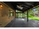 Covered patio with brick siding, and gray flooring leading out to a spacious green lawn at 7234 S Kendall Ct, Littleton, CO 80128