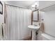 A charming bathroom featuring a pedestal sink, decorative mirror and shower with curtain at 14050 E 25Th Pl, Aurora, CO 80011