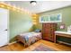 Cozy bedroom with hardwood floors, a single bed, dresser, desk and bright string lights at 14050 E 25Th Pl, Aurora, CO 80011