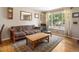 Cozy living room featuring hardwood floors, a comfortable couch, and a large window that allows natural light to flood the space at 14050 E 25Th Pl, Aurora, CO 80011