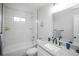 Well-lit bathroom with white tiled walls, a bathtub, and a modern vanity with granite countertop at 2696 S Grove St, Denver, CO 80219