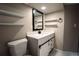 Bathroom featuring white vanity, toilet, shelving, mirror, and modern black fixtures at 4854 S Parfet St, Littleton, CO 80127