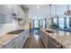 Contemporary kitchen with an island, stainless steel appliances, light gray cabinetry, and a view into dining and living areas at 14232 Elm St, Thornton, CO 80602