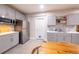 Modern kitchen features grey cabinets, stainless appliances, a wooden table, and a tiled backsplash at 14232 Elm St, Thornton, CO 80602