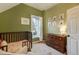 Green-walled Bedroom featuring a wooden crib, dresser, animal-themed art and window with natural light, creating a cozy space at 2244 N Washington St, Denver, CO 80205