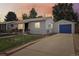 Charming single-story home with blue garage door, fenced yard, and a long driveway leading to a detached garage at 7940 Pontiac St, Commerce City, CO 80022