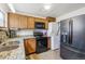 Kitchen featuring wood cabinets, granite counters, black appliances and stacked washer/dryer at 7940 Pontiac St, Commerce City, CO 80022