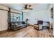 Bright living room featuring wood floors, a ceiling fan, a comfortable sofa, and a large window at 7940 Pontiac St, Commerce City, CO 80022
