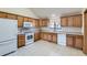 Efficient kitchen featuring ample oak cabinets, white appliances, and tile flooring at 2585 E Egbert St, Brighton, CO 80601