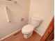 Compact bathroom featuring a white toilet, accessibility bar, and wood-look flooring at 2713 W Long Dr # C, Littleton, CO 80120