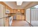 Kitchen with wood cabinets, white appliances, stainless dishwasher, and patio access at 2713 W Long Dr # C, Littleton, CO 80120