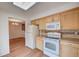 Bright kitchen with wood cabinets, white appliances, skylight, and an open view to the dining area at 2713 W Long Dr # C, Littleton, CO 80120