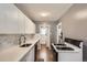 Bright kitchen features white cabinetry, marble backsplash, stainless sink and modern appliances at 3016 S Grape Way, Denver, CO 80222