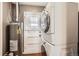Laundry room features stackable washer and dryer unit, water heater and storage space at 3016 S Grape Way, Denver, CO 80222