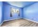 This bedroom has gray wood flooring, calming blue walls, and natural light from the large window at 16623 E Asbury Pl, Aurora, CO 80013