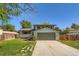 Charming two-story home with a two-car garage, framed by mature trees and a green lawn at 16623 E Asbury Pl, Aurora, CO 80013