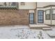 Close-up of townhome entrances featuring brick exterior, secure doors and snowy walkways at 1760 S Ammons St # D, Lakewood, CO 80232