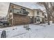 Charming townhome showcasing a brick facade, second-story deck and snowy front yard at 1760 S Ammons St # D, Lakewood, CO 80232